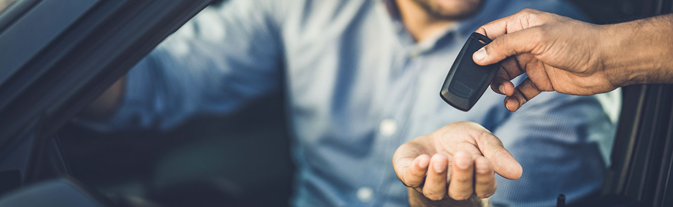 Man sitting in car and keys being put in his hand